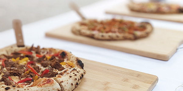 Plant-based pizzas on serving boards at a pizza buffet