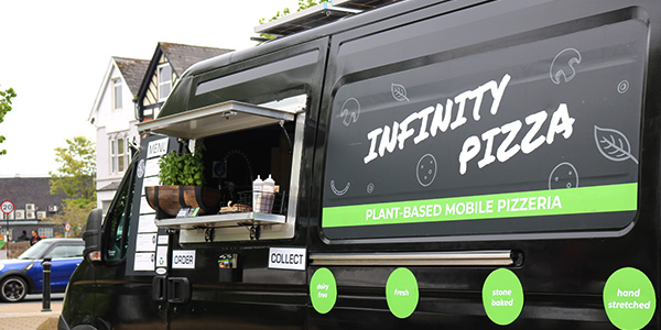 Black pizza van with serving hatch open and Infinity Pizza plant-based pizza decals